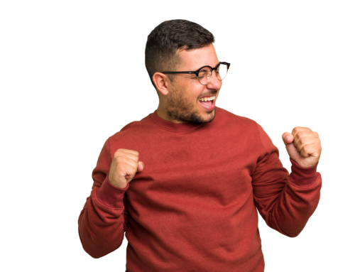 Young man wearing glasses and a red sweater raising his fists in celebration.