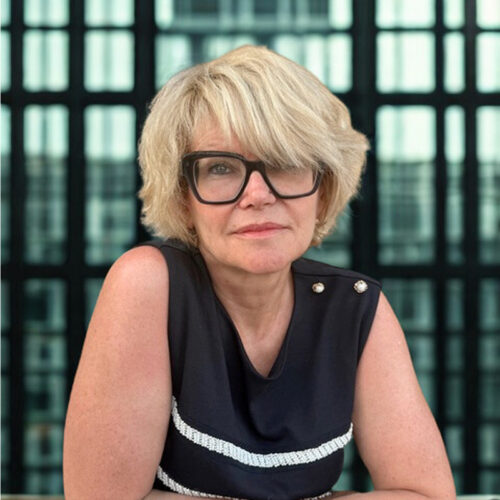Portrait of Bruno Witek wearing glasses and a striped shirt, seated indoors.